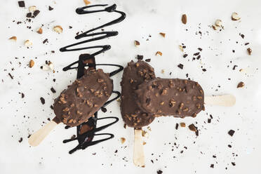 Drei Eiscreme-Riegel auf weißem Hintergrund, Schokoladenstreusel und Nüsse - CAVF80280