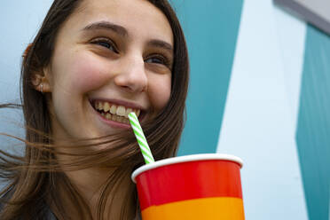 Woman smiling and drinking soda with a straw at a party. - CAVF80339