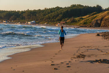Junges sportliches Mädchen läuft am Strand - CAVF80383