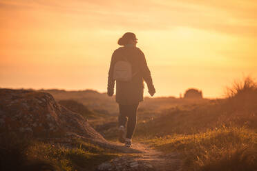 Frau beim Spaziergang bei Sonnenuntergang im Naturpark Corrubedo, Galica, Spanien - CAVF80457