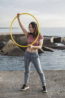 Glückliche Frau spielt mit Hula-Hoop-Reifen am Hafen - XLGF00076