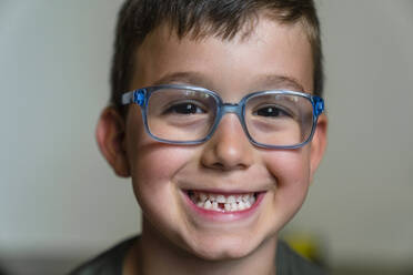 Porträt eines kleinen Jungen mit Zahnlücke und blauer Brille - MGIF00908