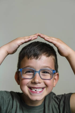 Porträt eines kleinen Jungen mit Zahnlücke und blauer Brille, lizenzfreies Stockfoto