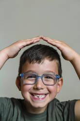 Portrait of little boy with tooth gap wearing blue glasses - MGIF00909