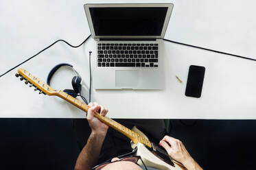 Draufsicht auf einen Mann, der mit einem Laptop online E-Gitarre spielen lernt - JCMF00617