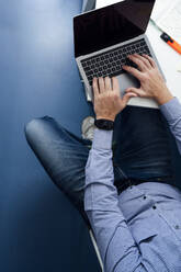 Tiefschnitt eines Mannes, der im Büro sitzt und auf einem Laptop tippt - JCMF00627