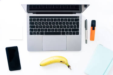 Banana lying in front of laptop - JCMF00629
