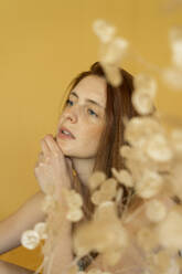 Portrait of pensive redheaded woman against yellow background - AFVF06160