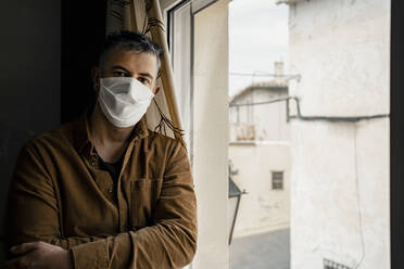 Man wearing protective mask and looking out of the window - RCPF00232