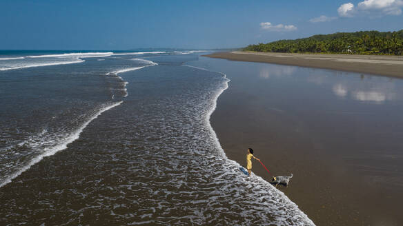 Junge Frau geht mit ihrem Hund am Strand spazieren, Costa Rica - AMUF00089