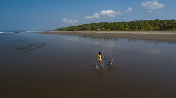 Unbekümmerte junge Frau geht mit ihrem Hund am Strand spazieren, Costa Rica - AMUF00091