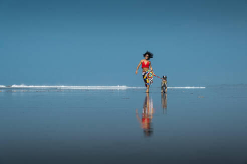 Unbekümmerte junge Frau geht mit ihrem Hund am Strand spazieren, Costa Rica - AMUF00093