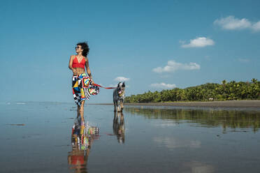 Young woman taking her dog for a walk at the beach, Costa Rica - AMUF00096