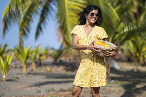 Young woman holding a fruit basket at the beach, Costa Rica stock photo