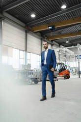 Businessman walking in a factory - DIGF09916