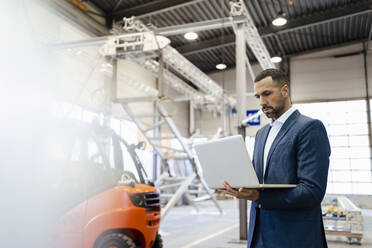 Businessman using laptop in a factory - DIGF09927