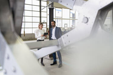 Businessman and young woman with tablet talking in a factory - DIGF09962