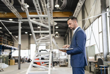 Businessman using laptop in a factory - DIGF09971