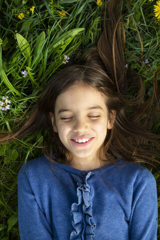 Portrait of girl with eyes closed relaxing on a meadow in spring stock photo