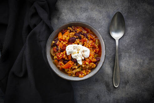 Schüssel mit vegetarischem Chili mit roten Linsen, Kidneybohnen, Tomaten, Karotten, Sellerie und saurer Sahne - LVF08856