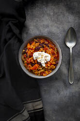 Bowl of vegetarian chili with red lentils, kidney beans, tomatoes, carrots, celery and sour cream - LVF08857