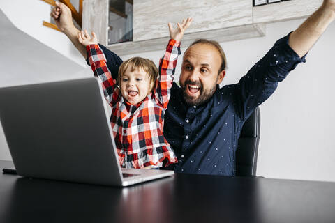 Glücklicher Vater mit Tochter bei einem Videochat am Schreibtisch, lizenzfreies Stockfoto