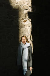 Porträt einer lächelnden Frau, die im Sonnenlicht zwischen Schatten steht, Barcelona, Spanien - XLGF00089