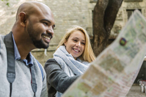Porträt einer glücklichen Frau, die zusammen mit ihrem Freund einen Stadtplan betrachtet, Barcelona, Spanien, lizenzfreies Stockfoto