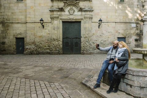 Paar macht Selfie mit Smartphone am Sant Felip Neri Platz, Barcelona, Spanien, lizenzfreies Stockfoto
