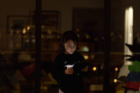 Junge benutzt Tablet zu Hause in der Nacht, lizenzfreies Stockfoto