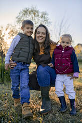 Porträt einer glücklichen Mutter mit zwei Kindern im Garten - ZEDF03340
