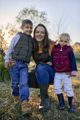 Portrait of happy mother with two kids in garden - ZEDF03340