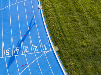 Aerial view of runner on blue tartan track - STSF02522