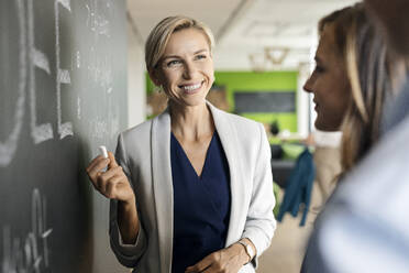 Businesswoman brainstorming at blackboard in office - PESF01954