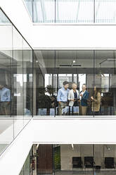 Geschäftsfrau und Angestellte unterhalten sich hinter einer Fensterscheibe im Büro - PESF01978