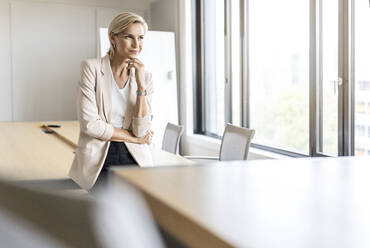 Blond businesswoman in conference room thinking - PESF01998