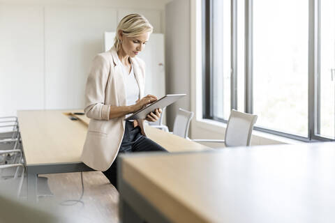 Blonde Geschäftsfrau mit Tablet im Konferenzraum, lizenzfreies Stockfoto