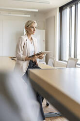 Blond businesswoman holding tablet in conference room - PESF02000