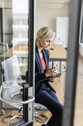 Blond businesswoman using tablet in conference room - PESF02014