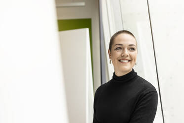 Portrait of smiling young woman at the window in office - PESF02025