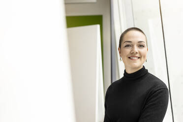 Portrait of smiling young woman at the window in office - PESF02026