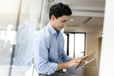 Young businessman using tablet at the window in office - PESF02030