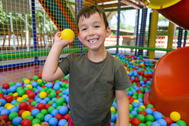Lächelnder Junge wirft Ball in Ballgrube - MGIF00911