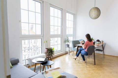 Woman sitting at table at home looking at photographs stock photo