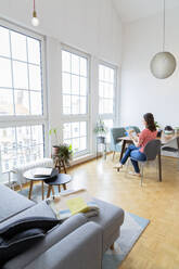 Woman sitting at table at home looking at photographs - FKF03723