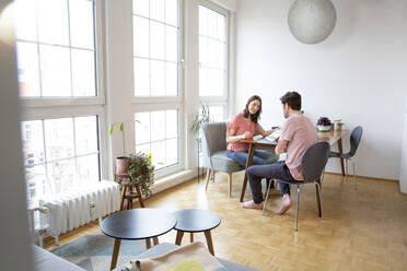 Couple sitting at table at home talking - FKF03737