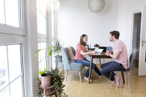 Ehepaar sitzt zu Hause am Tisch und unterhält sich, lizenzfreies Stockfoto