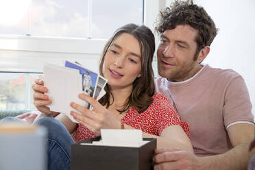 Couple looking at photographs at home - FKF03747