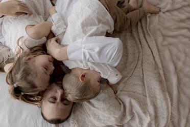 Father lying on bed cuddling with his two children - GMLF00122