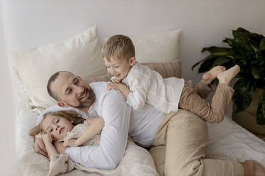 Family portrait of happy father and his two children at home - GMLF00131